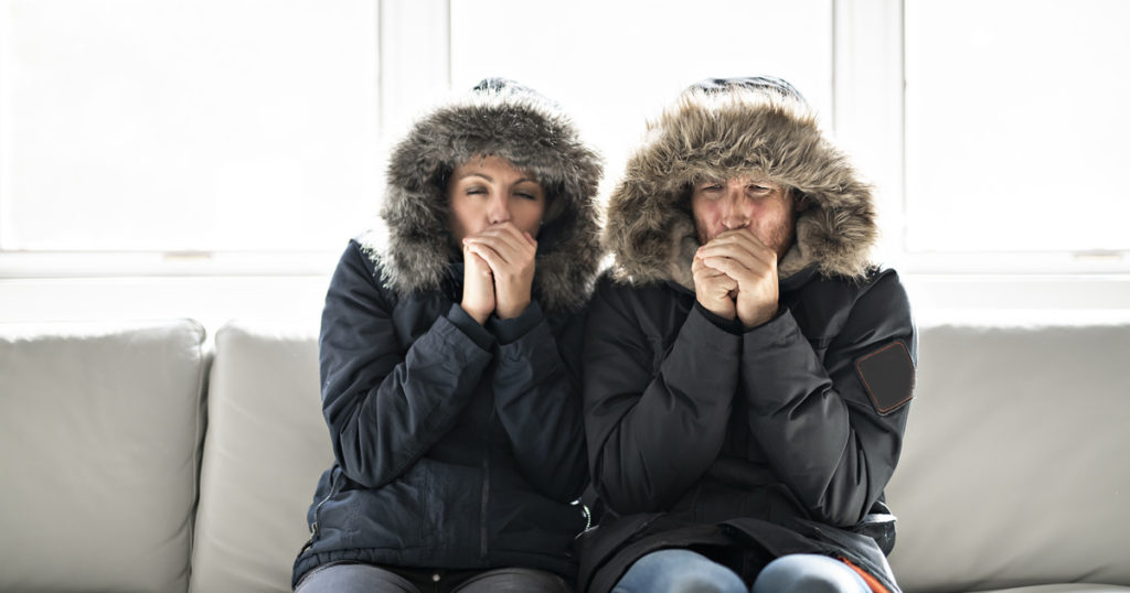 A couple wearing coats sitting on a sofa