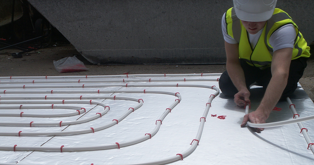 man clipping pipe onto insulation board