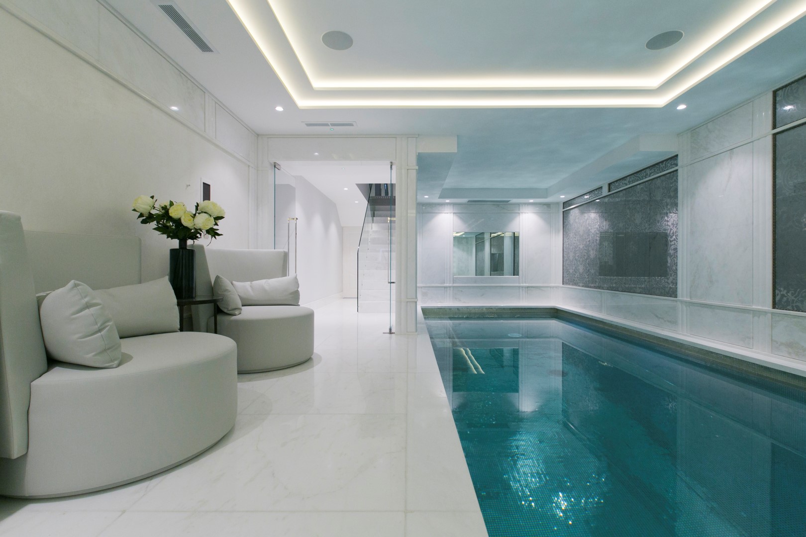 Indoor Swimming Pool With White Marble Floors And White Furniture