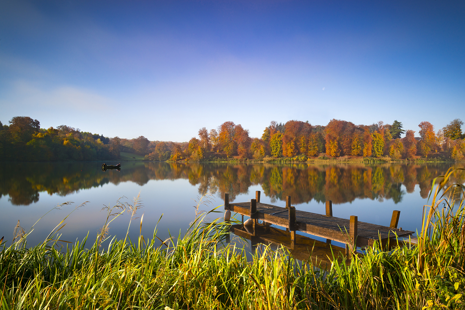 Lake In The Sun With A Small Boat And Wooden Pier