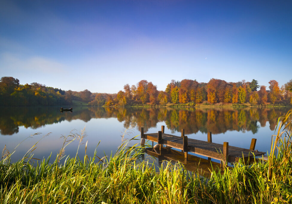 Lake In The Sun With A Small Boat And Wooden Pier
